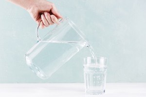 Wasser wird aus Krug in Glas gefüllt.